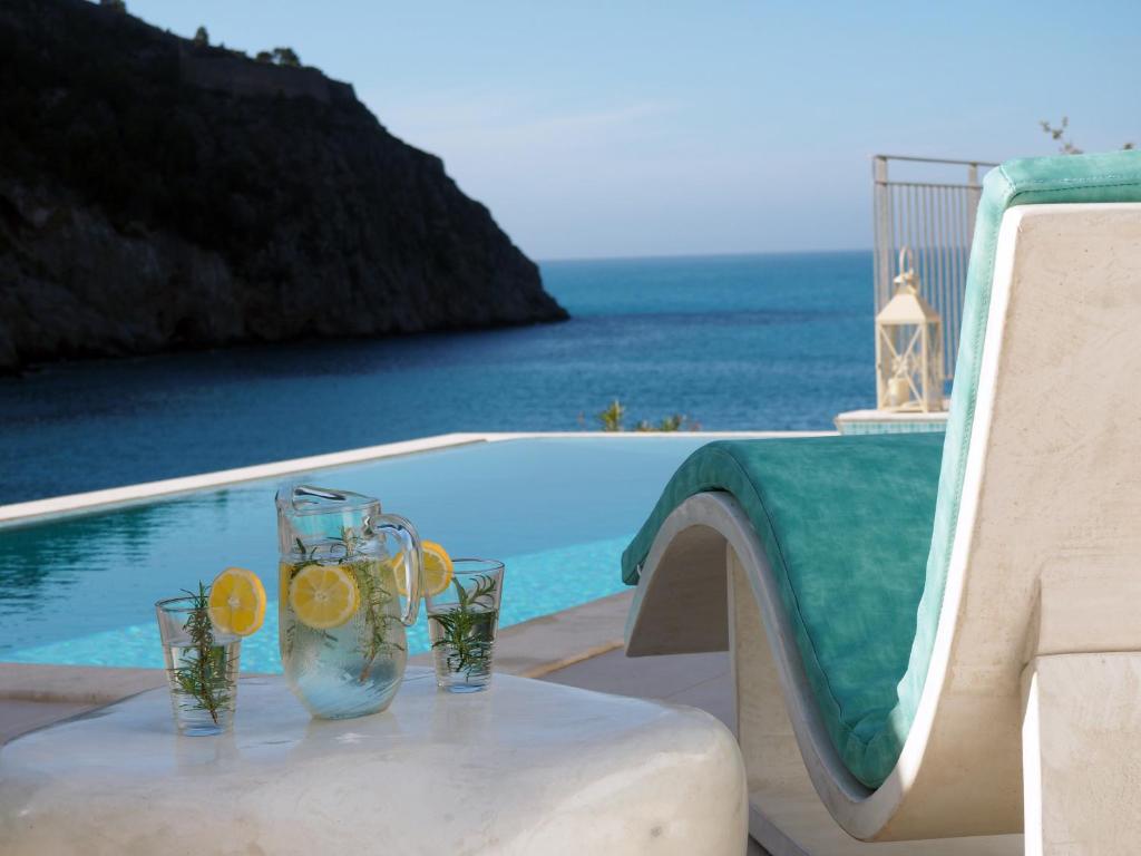 a table with glasses with lemon slices on it next to a pool at Assos View in Asos