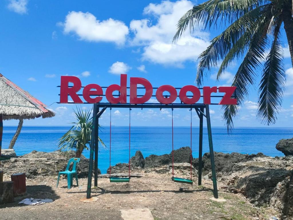 a sign that reads red door on a beach at RedDoorz Syariah near Ujong Kareung Beach Sabang in Kota Bawah Timur