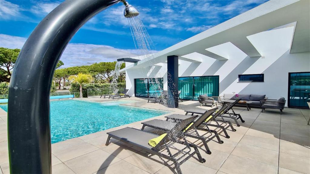 a swimming pool with chairs and a building at Villa Waterfall - Clever Details, luxury, 5min walking from the center in Vilamoura