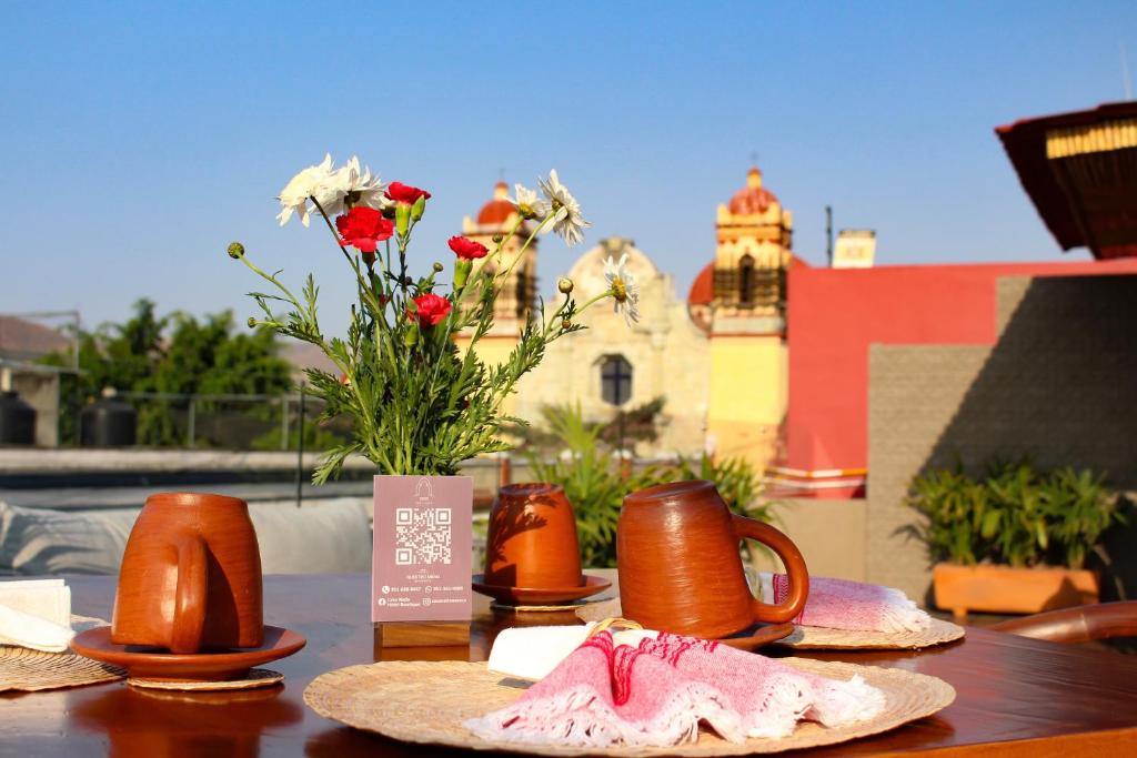 a table with cups and a vase with flowers on it at Casa Naila Hotel Boutique in Oaxaca City