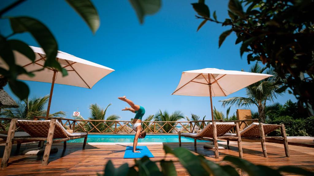 a woman is jumping into a swimming pool at Sansi Kendwa Beach Resort in Kendwa