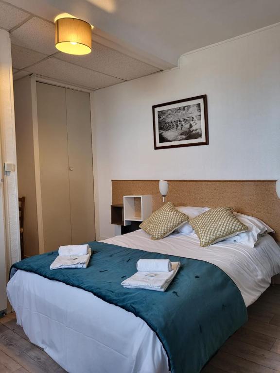 a bedroom with a large bed with towels on it at Hotel de Normandie in Saint-Aubin-sur-Mer