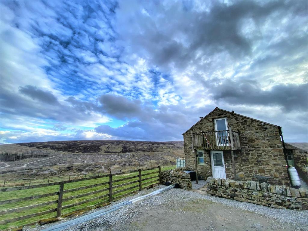 an old stone building with a balcony on a hill at Mandy's Cottage Lanehead - Rural Escape in Bishop Auckland