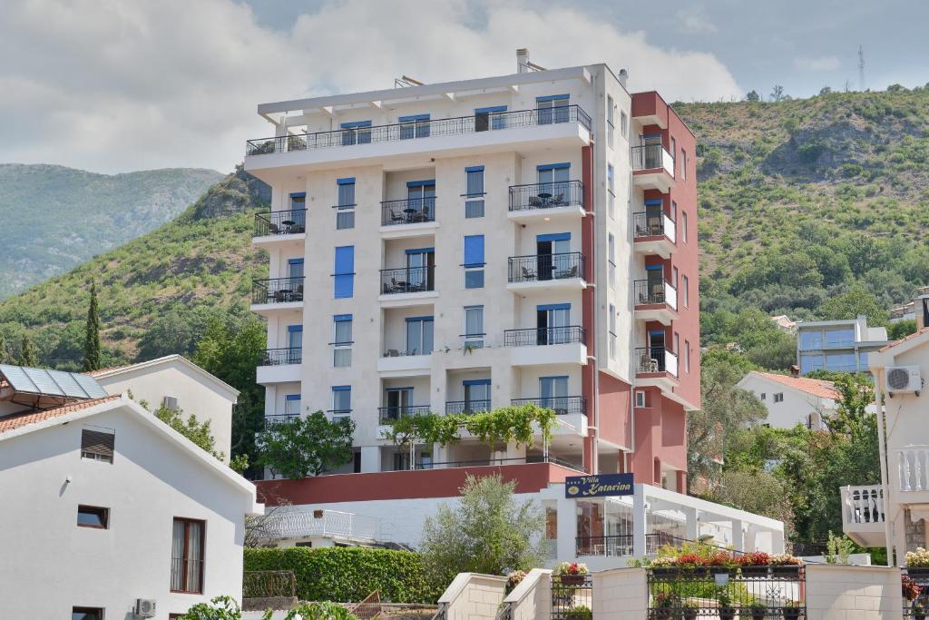 a tall white building with blue windows at Villa Katarina in Budva