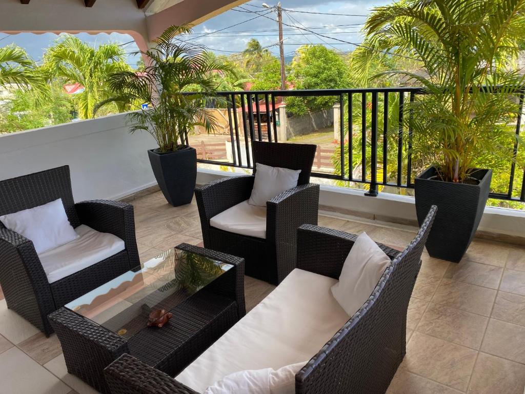 a balcony with wicker chairs and a coffee table at Chez Soul~Etage entier avec vue sur mer in Sainte-Rose