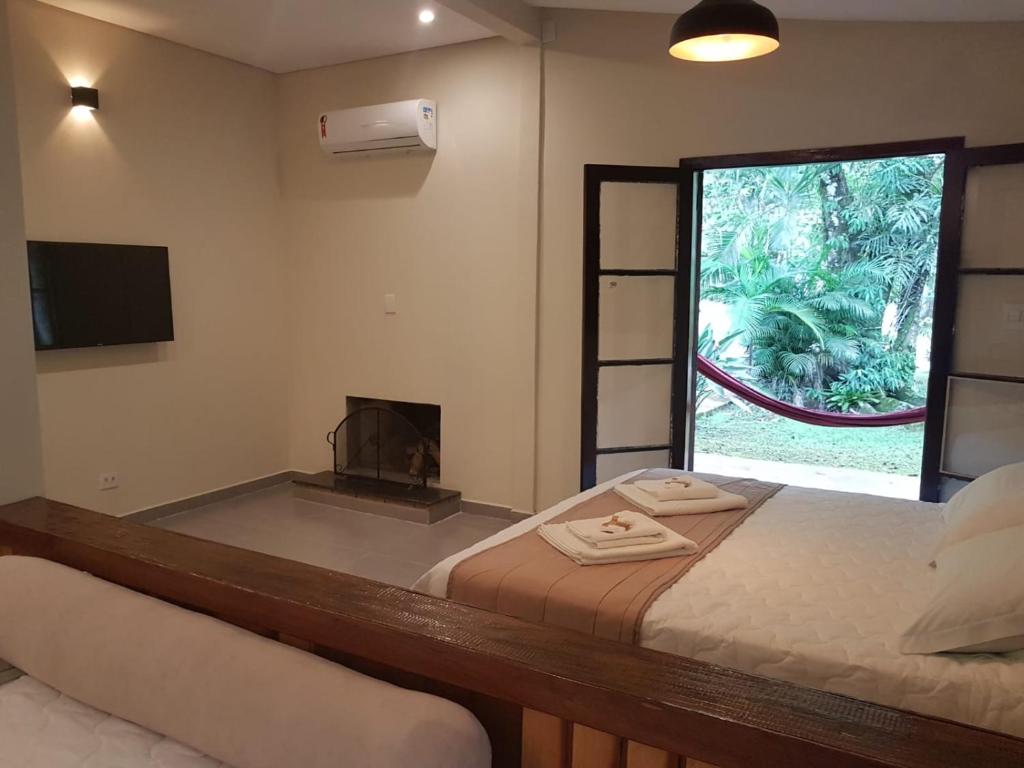 um quarto com 2 camas, uma lareira e uma janela em Gamboa Eco Refugio Pousada em Iporanga