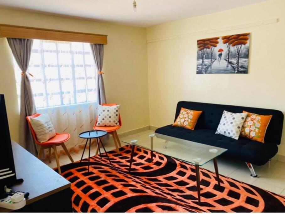 a living room with a blue couch and orange chairs at Lovely apartment near town with WiFi and parking in Meru