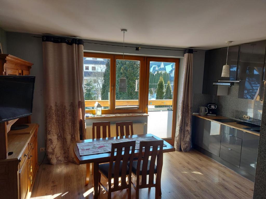 kuchnia ze stołem i krzesłami oraz oknem w obiekcie Apartament Zakopane Kamieniec 10i w Zakopanem