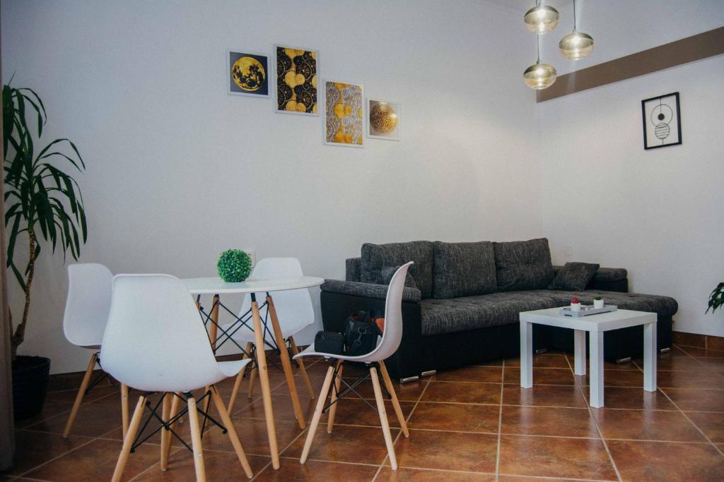 sala de estar con sofá, mesa y sillas en Rakoczi apartman 2 en Odorheiu Secuiesc