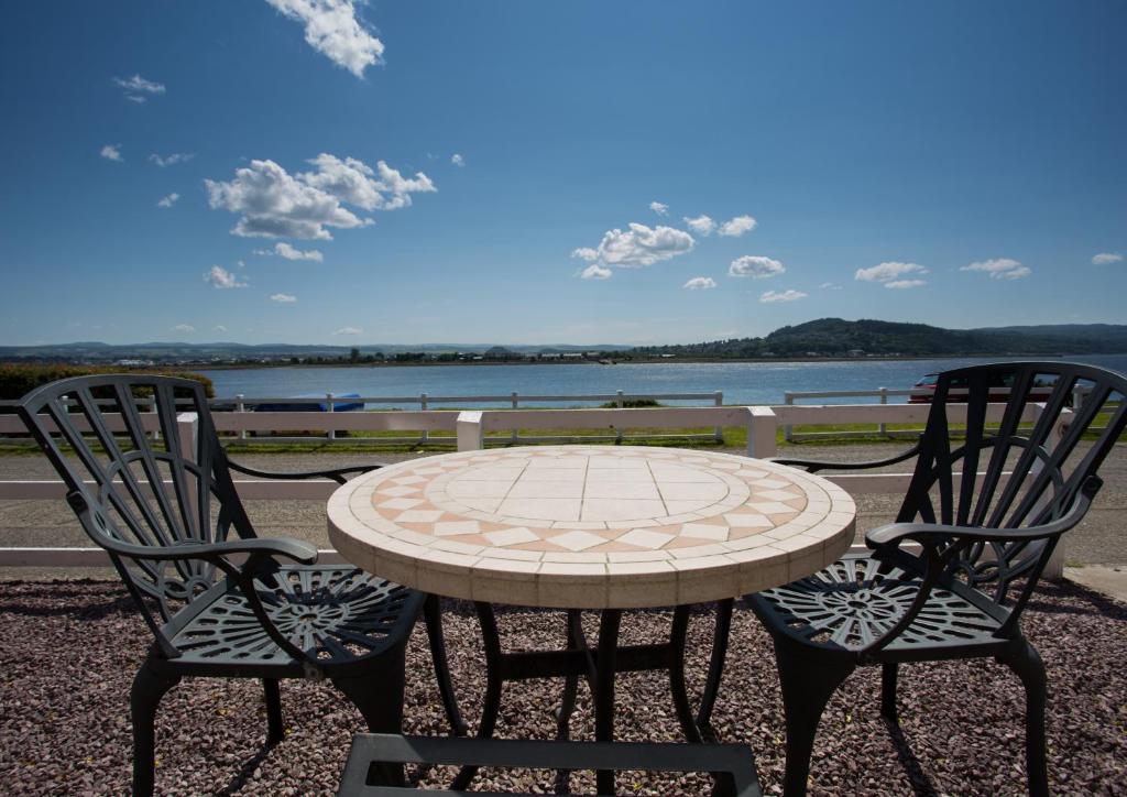 einen Tisch und zwei Stühle mit einem Tisch und einem See in der Unterkunft Shore View Cottage in Inverness