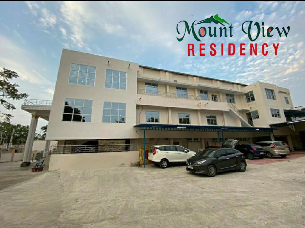 ein großes Gebäude mit Autos auf einem Parkplatz in der Unterkunft Mount View Residency Tiruttani in Tiruttani