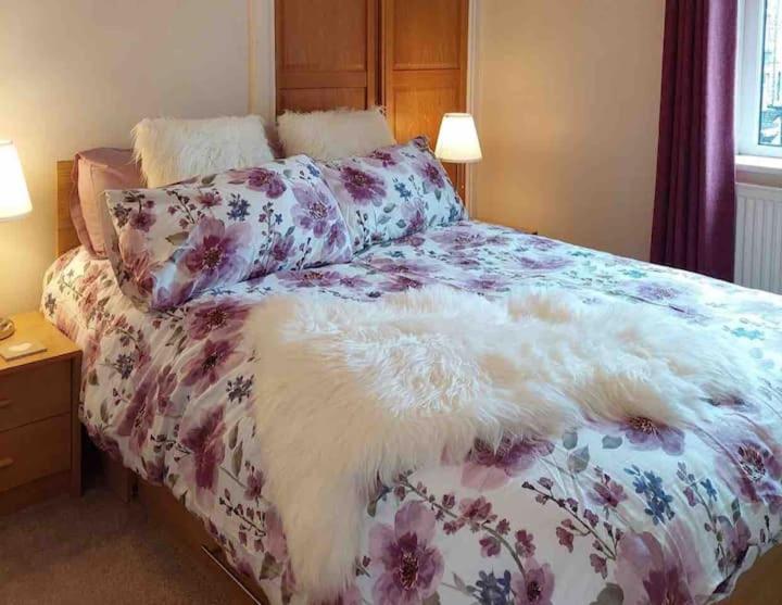 a bed with a floral blanket and pillows on it at Boutique Cottage In The Heart Of Buxton Town in Buxton