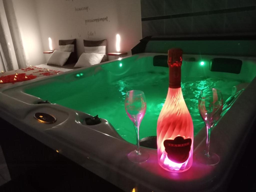a hot tub with two wine glasses and a bottle at Nuit romantique avec Jacuzzi SPA privatif proche TOULOUSE in Auterive