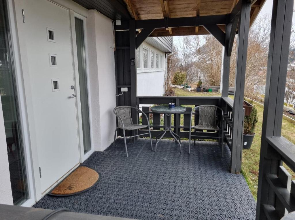 un porche cubierto con mesa y sillas en Holiday apartment, en Kleppstad
