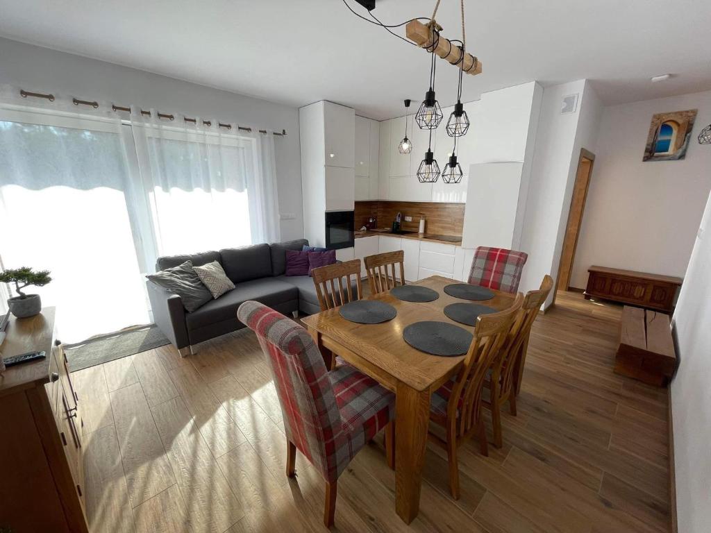 een keuken en een woonkamer met een tafel en stoelen bij Luxoro Park Apartament Nero in Ustka