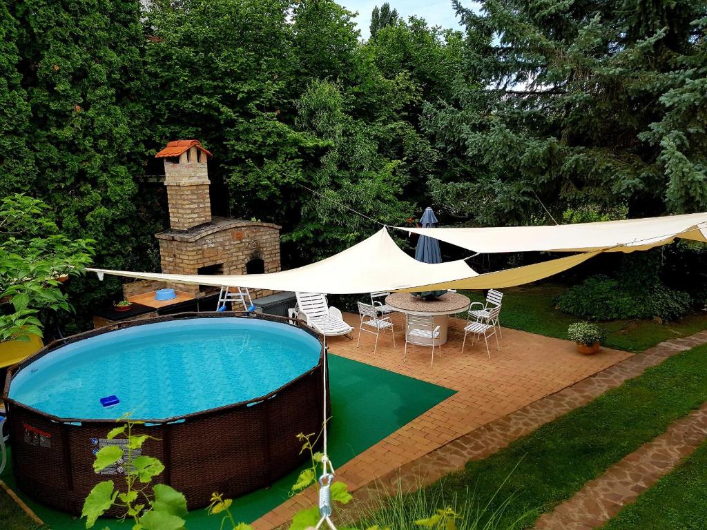 a tent over a swimming pool with a table and chairs at Borostyán Apartmann in Balatonföldvár