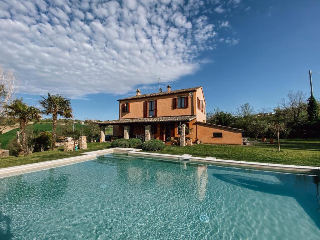 una casa con una gran piscina frente a una casa en Casale Il Girasole, en San Costanzo