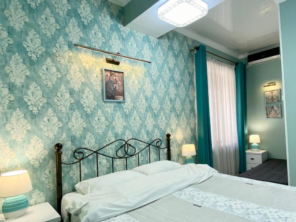 a bedroom with a bed and a blue wall at Hotel Nicolas in Tbilisi City