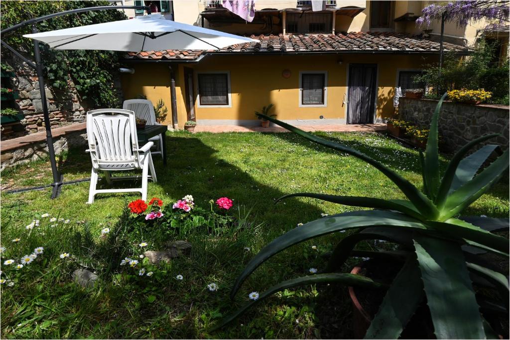 einen Garten mit einem Stuhl, einem Regenschirm und Blumen in der Unterkunft Appartamento i Cipressi in Figline Valdarno