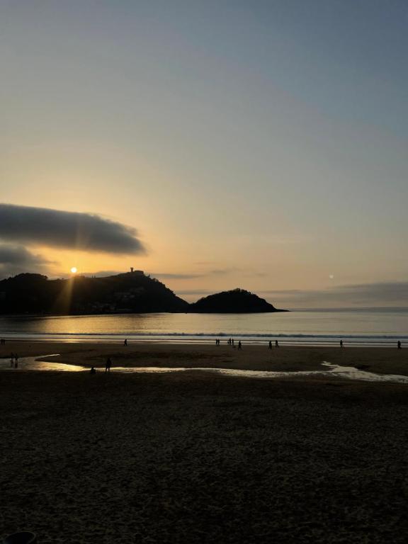 um grupo de pessoas caminhando na praia ao pôr do sol em Pensión Artea em San Sebastián