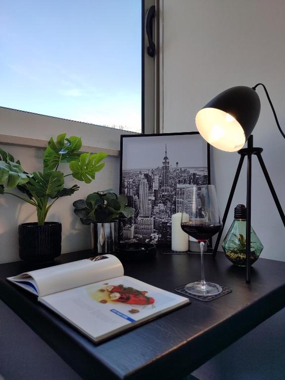 a desk with a book and a lamp and a glass of wine at Apartman Ivan in Kaštela