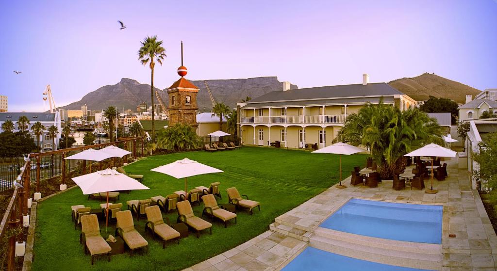 a resort with a pool and chairs and a clock tower at Dock House Boutique Hotel and Spa by NEWMARK in Cape Town