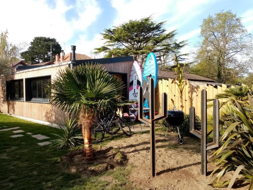 ein Haus mit Surfbrettern und einer Palme im Hof in der Unterkunft Un petit coin de paradis in Saint-Brevin-les-Pins