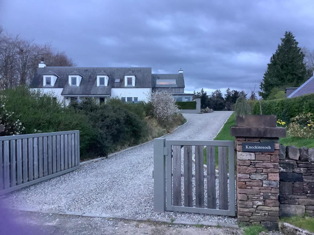 a gate on a gravel road with houses in the background at Knockinreoch in Drymen