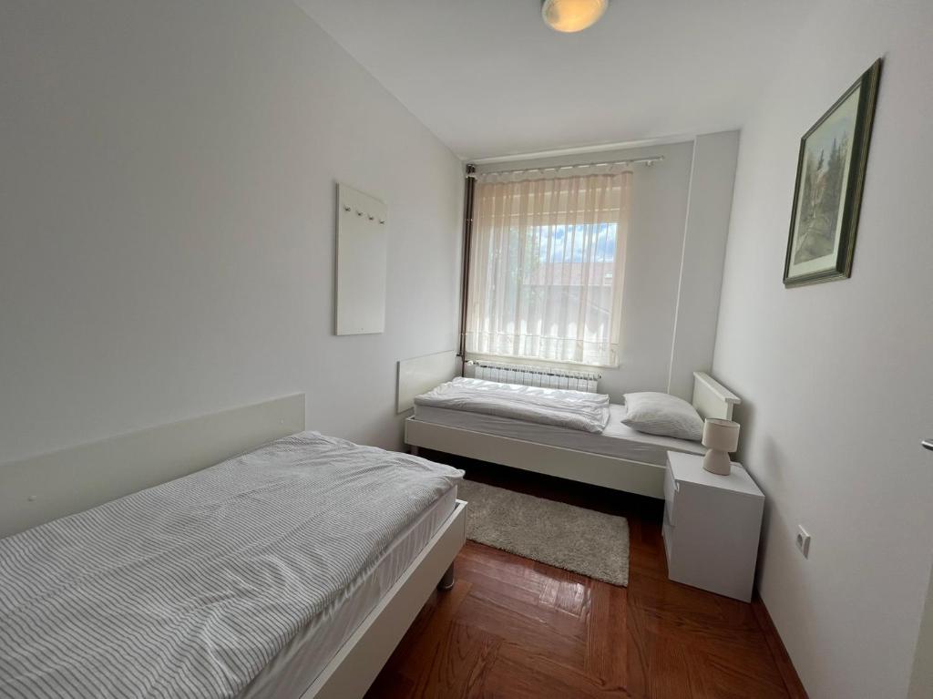 - une petite chambre avec 2 lits et une fenêtre dans l'établissement Apartmani Nova, à Karlovac