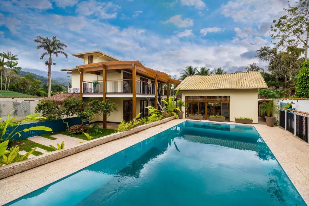 una casa con piscina di fronte a una casa di Canto do Ilé Dive & Lodge a Parati