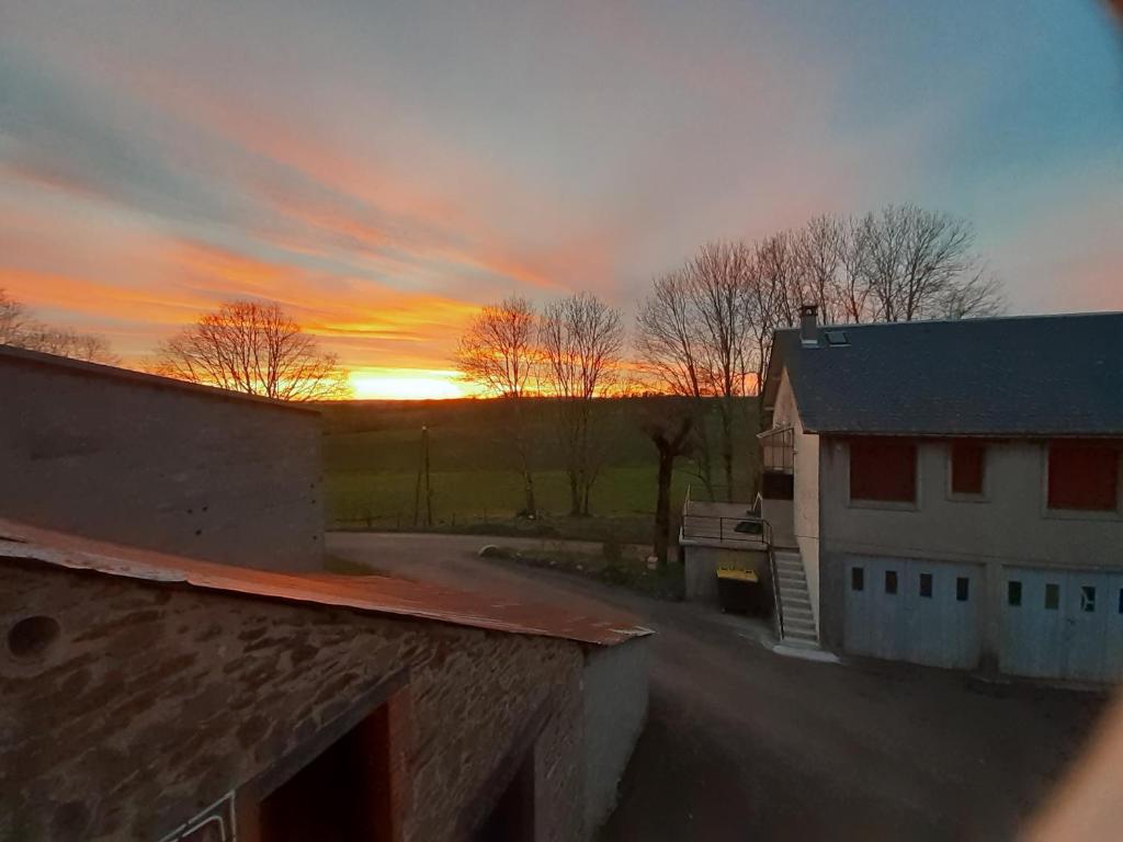 a sunset over a house and a road with trees at Le Nid des Avezous in Avèze