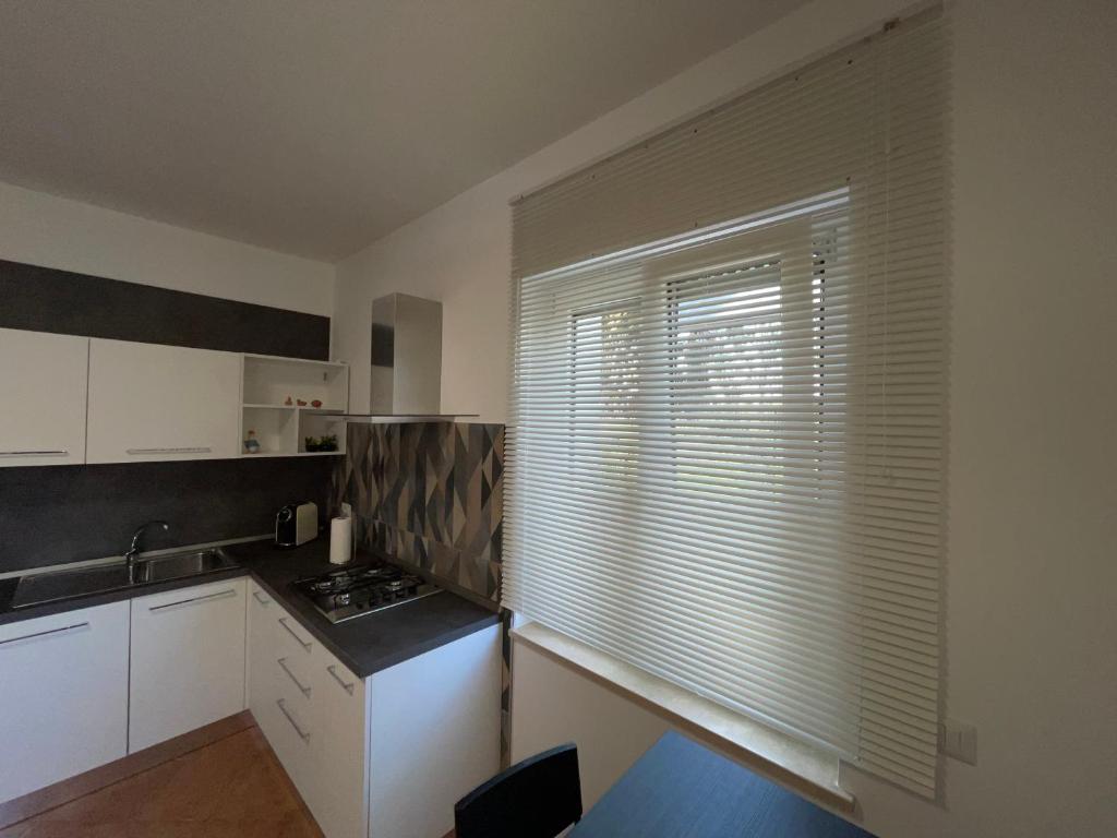 una cocina con armarios blancos y una ventana con persianas en Casa vacanze La Castellana, en Pianella