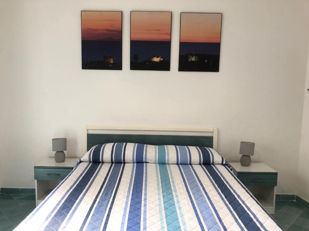 a bedroom with a bed with three pictures on the wall at Casetta Forio in Forio d'Ischia