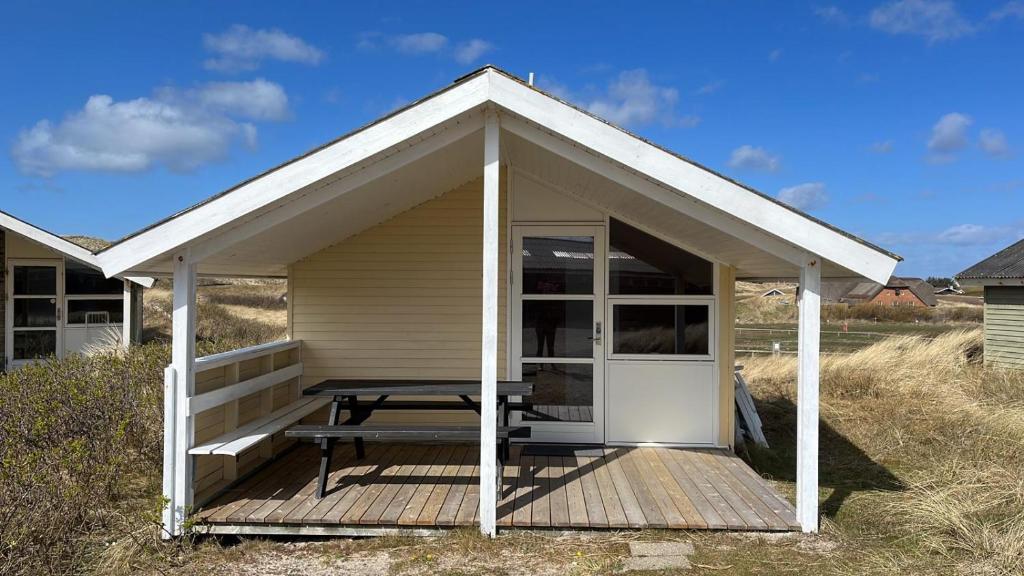 um pequeno barracão com uma mesa de piquenique num deque em Dancamps Holmsland em Hvide Sande