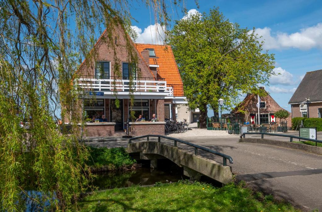 un bâtiment avec un pont en face d'une rivière dans l'établissement The Lake Inn, à Nieuwkoop