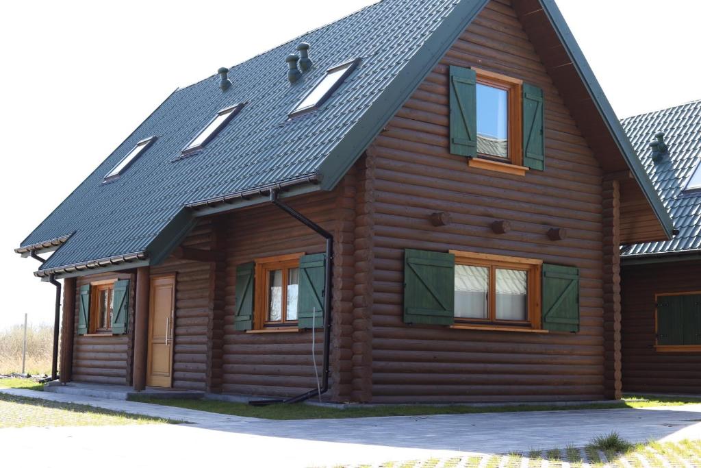 Casa de madera con techo negro y ventanas en Dzikie Gąski en Gąski