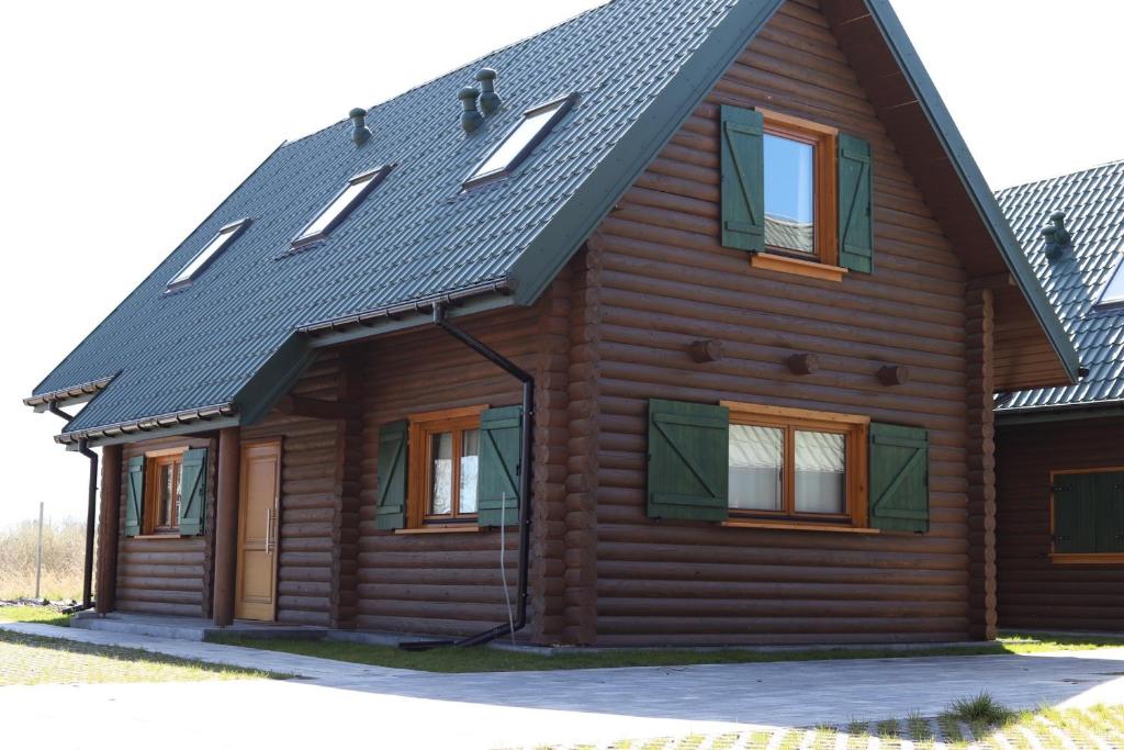 a wooden house with a black roof and windows at Dzikie Gąski in Gąski
