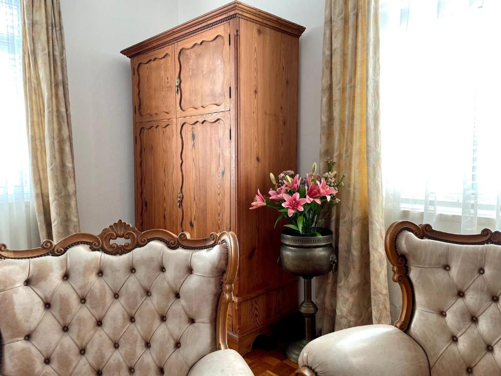 a room with a chair and a cabinet with flowers at Casa Às Oito in Angra do Heroísmo