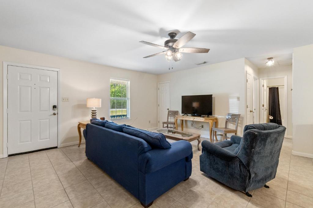a living room with two blue chairs and a tv at Island House in Dauphin Island