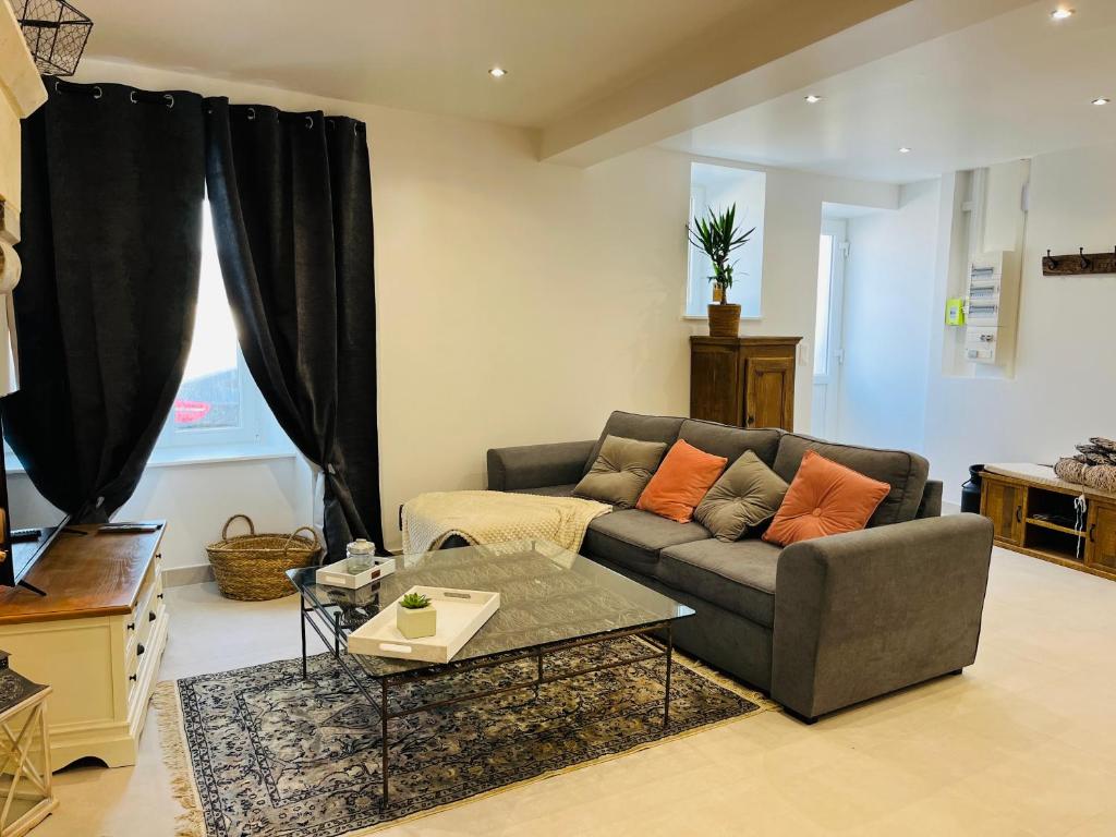 uma sala de estar com um sofá e uma mesa em La Casa D'Alauna em Valognes