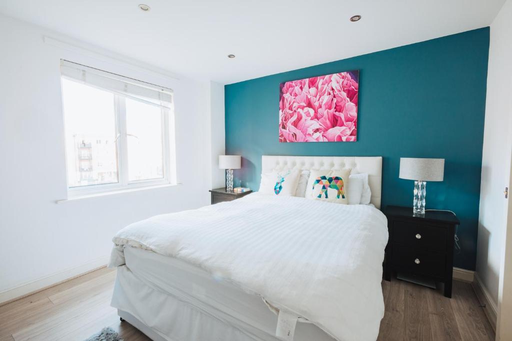 1 dormitorio con cama blanca y pared azul en Beautiful Central Family Apartment for 6 en Londres