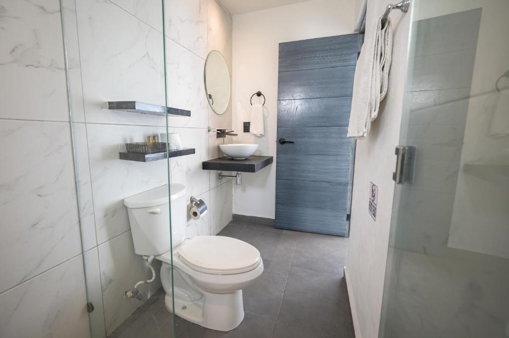 Un baño blanco con inodoro y lavabo. en Aruma Suites, en Playa del Carmen