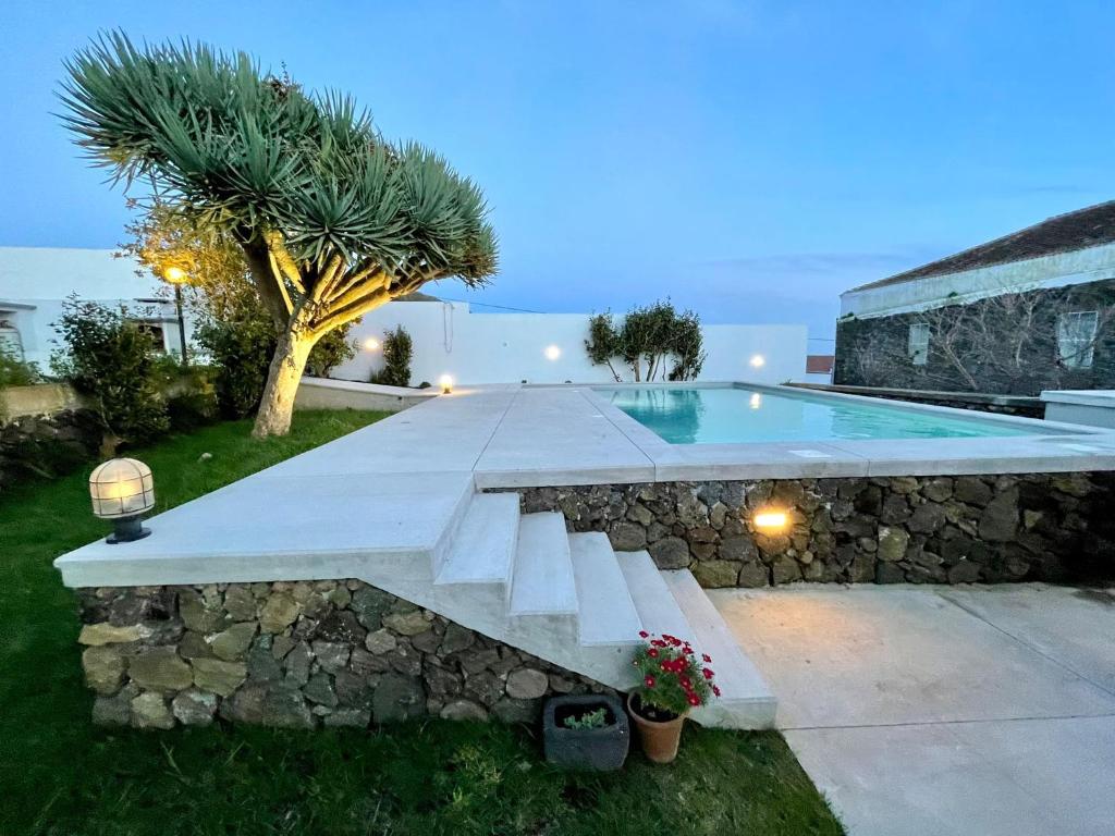 a swimming pool with a bench next to a stone wall at Casa Às Dez in Angra do Heroísmo