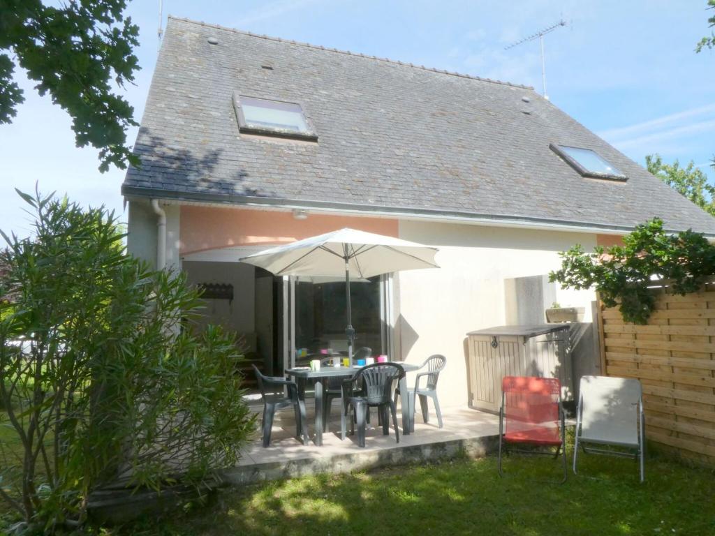 une terrasse avec une table, des chaises et un parasol dans l'établissement Holiday home, Beg Meil, à Fouesnant