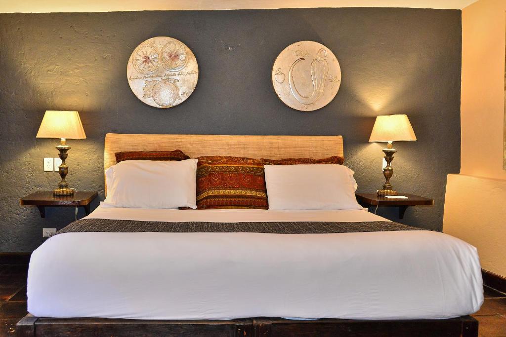 a bedroom with a large bed with two pictures on the wall at Hotel Mesones 49 in San Miguel de Allende