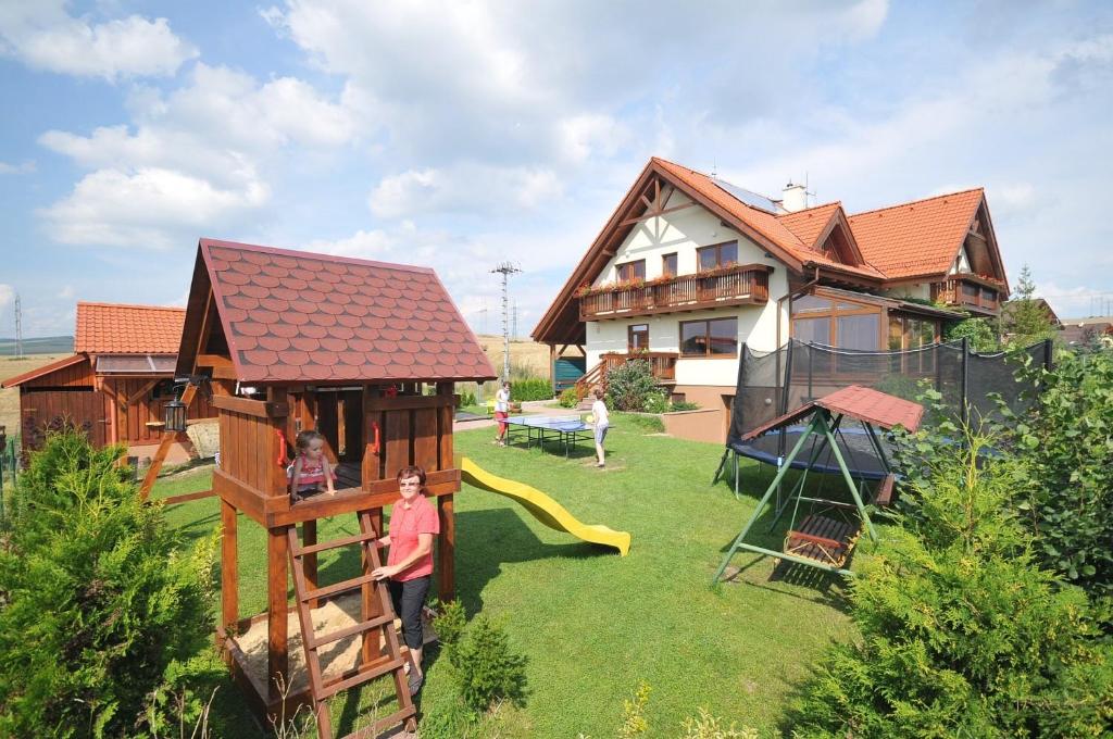 a house with a playground in the yard at Penzion Úsmev in Arnutovce