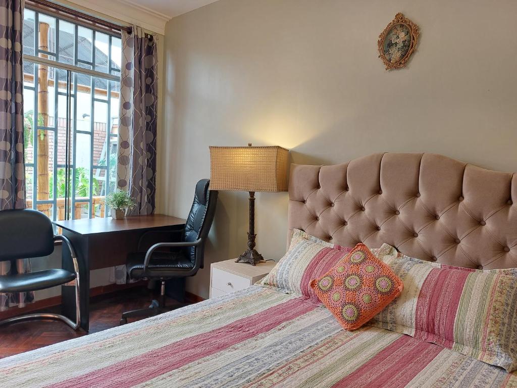 a bedroom with a large bed with a desk and a chair at Casa Amarello in Lima