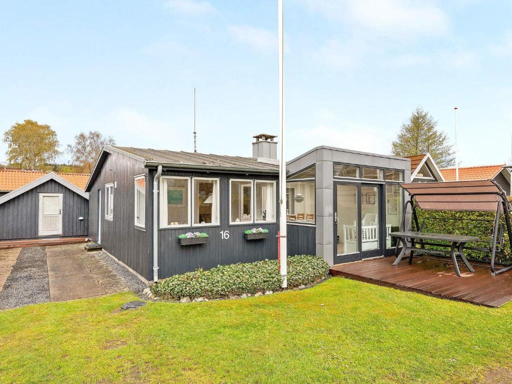 ein graues Haus mit einer Terrasse und einer Bank in der Unterkunft Holiday home Sjølund XXI in Sjølund