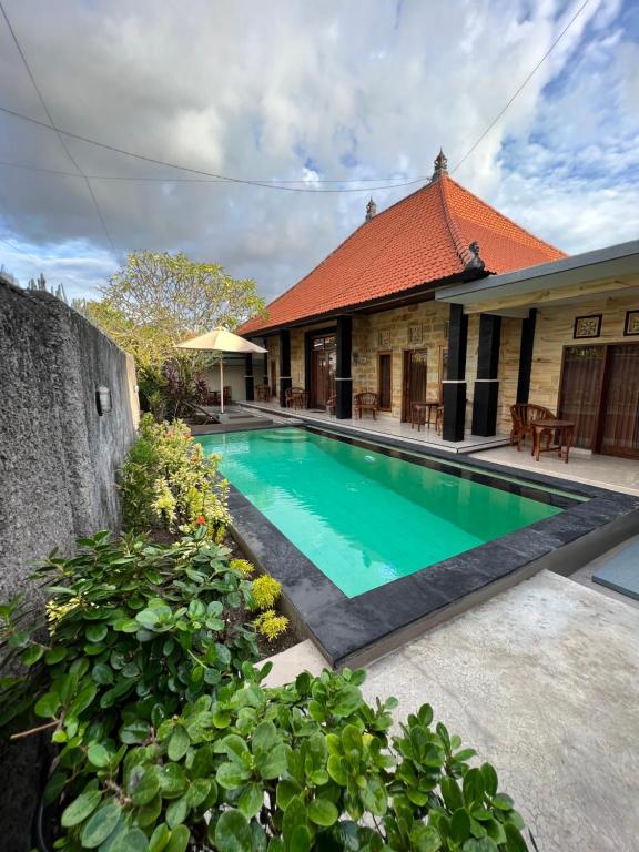 a swimming pool in front of a house at Nari Homestay in Canggu