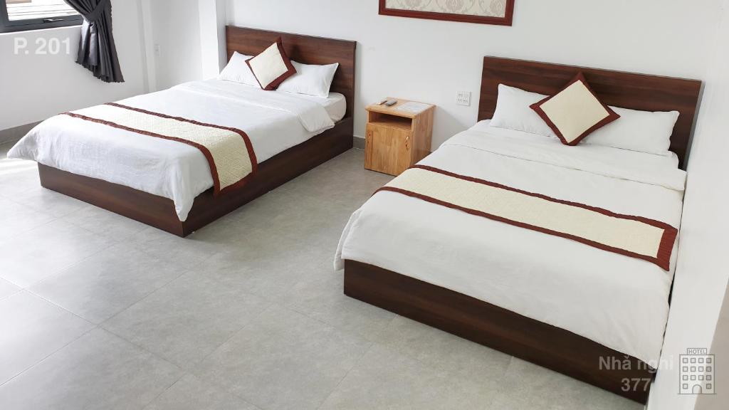 2 camas en una habitación con paredes blancas en Nhà nghỉ 377, en Bao Loc